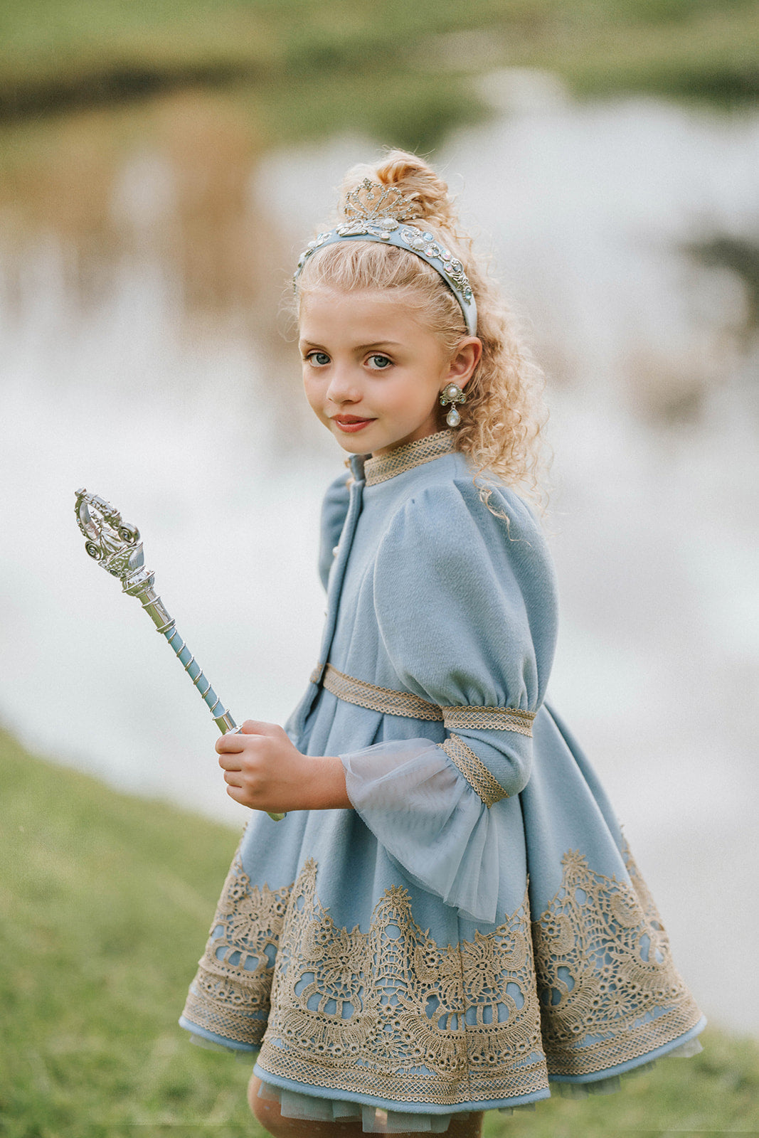 Victorian-inspired blue girls dress with gold embroidery, puff sleeves, and pearl buttons, perfect for birthdays or special occasions

Elegant heirloom girls dress in dusty blue with gold lace trim and tulle layers, hanging on ornate vintage-style mirror

Long sleeve blue and gold embroidered holiday dress for girls, featuring pearl buttons and layered tulle hem