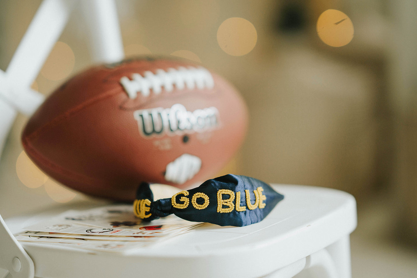 Girl wearing black “Go Blue” headband holding football on grassy field, dressed in white tee and denim shorts for game day

Child showing school spirit in sparkly “Go Blue” headband and football face sticker, styled for sports team support

Little girl wearing team pride headband that says “Go Blue” while smiling and holding a Wilson football outdoors

Blonde girl in football fan outfit with “Go Blue” headband and face paint, standing on a green field during sunset