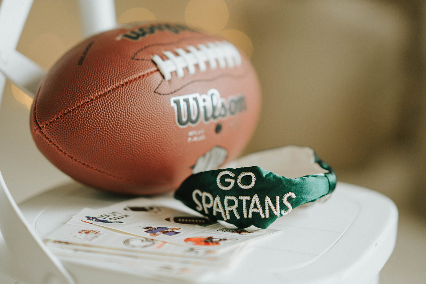 Girl wearing green “Go Spartans” headband holding a football on a grassy field at sunset, dressed in white tee and denim shorts

Child in team spirit outfit with green “Go Spartans” headband and football, perfect for game day or school pep rally

Little girl showing Spartan pride with beaded green headband and football, styled for fall sports or tailgate season

Girls football fan look with sparkly “Go Spartans” headband and casual outfit, standing in a field at golden hour