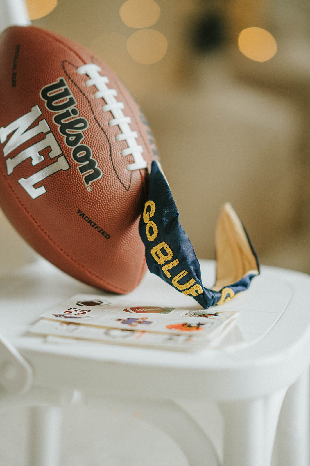 Girl wearing black “Go Blue” headband holding football on grassy field, dressed in white tee and denim shorts for game day

Child showing school spirit in sparkly “Go Blue” headband and football face sticker, styled for sports team support

Little girl wearing team pride headband that says “Go Blue” while smiling and holding a Wilson football outdoors

Blonde girl in football fan outfit with “Go Blue” headband and face paint, standing on a green field during sunset
