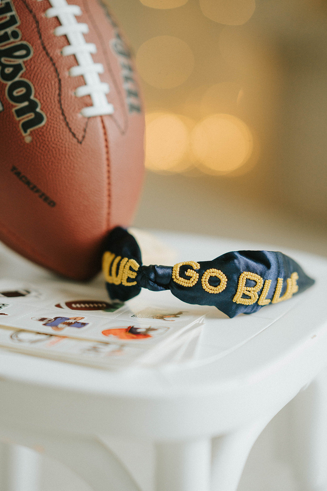 Girl wearing black “Go Blue” headband holding football on grassy field, dressed in white tee and denim shorts for game day

Child showing school spirit in sparkly “Go Blue” headband and football face sticker, styled for sports team support

Little girl wearing team pride headband that says “Go Blue” while smiling and holding a Wilson football outdoors

Blonde girl in football fan outfit with “Go Blue” headband and face paint, standing on a green field during sunset