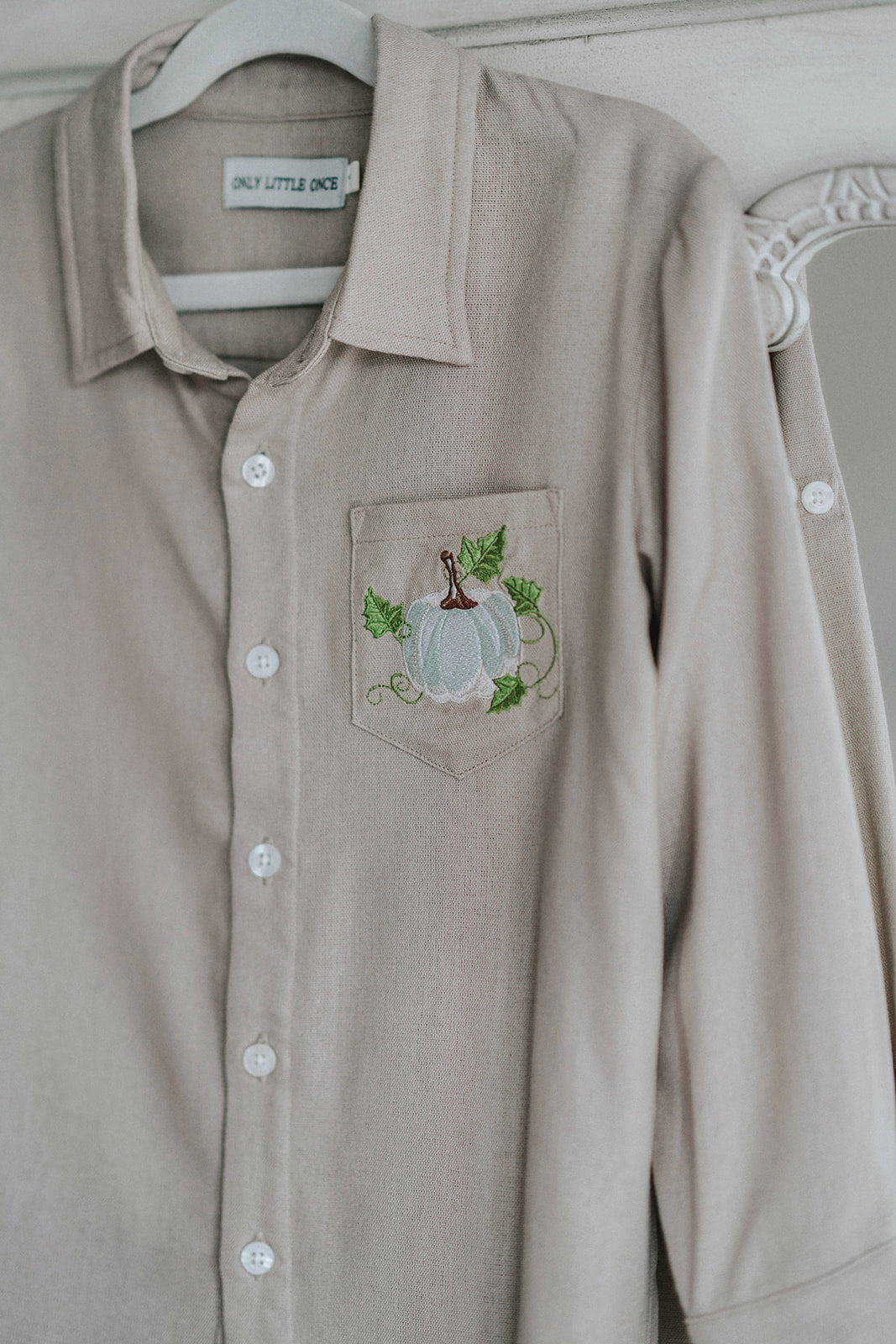 Boys beige button-up shirt with embroidered white pumpkin on chest pocket, hanging on vintage carved mirror for fall or Thanksgiving

Neutral boys fall shirt with embroidered pumpkin on pocket, styled for autumn photos, Thanksgiving, or sibling matching sets

Classic boys button-down shirt in light tan with embroidered blue pumpkin, perfect for harvest season or family portraits

Fall button-up shirt for toddlers and boys with embroidered pumpkin pocket detail, styled for Thanksgiving and heirloom outfits


