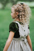 Heirloom-style green velvet holiday dress with linen pinafore and pumpkin embroidery, styled for autumn or fairytale dress-up
