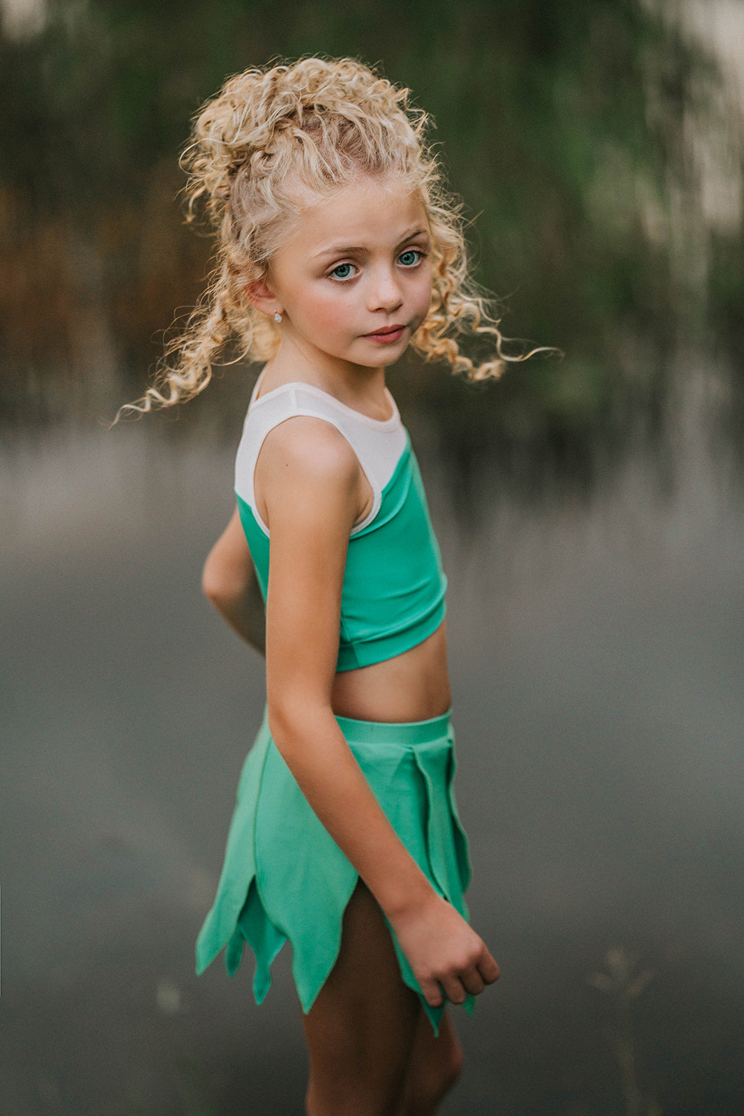 Child in green leaf skirt and matching top posing outdoors, perfect fairy or nature-themed costume for girls