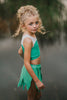 Child in green leaf skirt and matching top posing outdoors, perfect fairy or nature-themed costume for girls