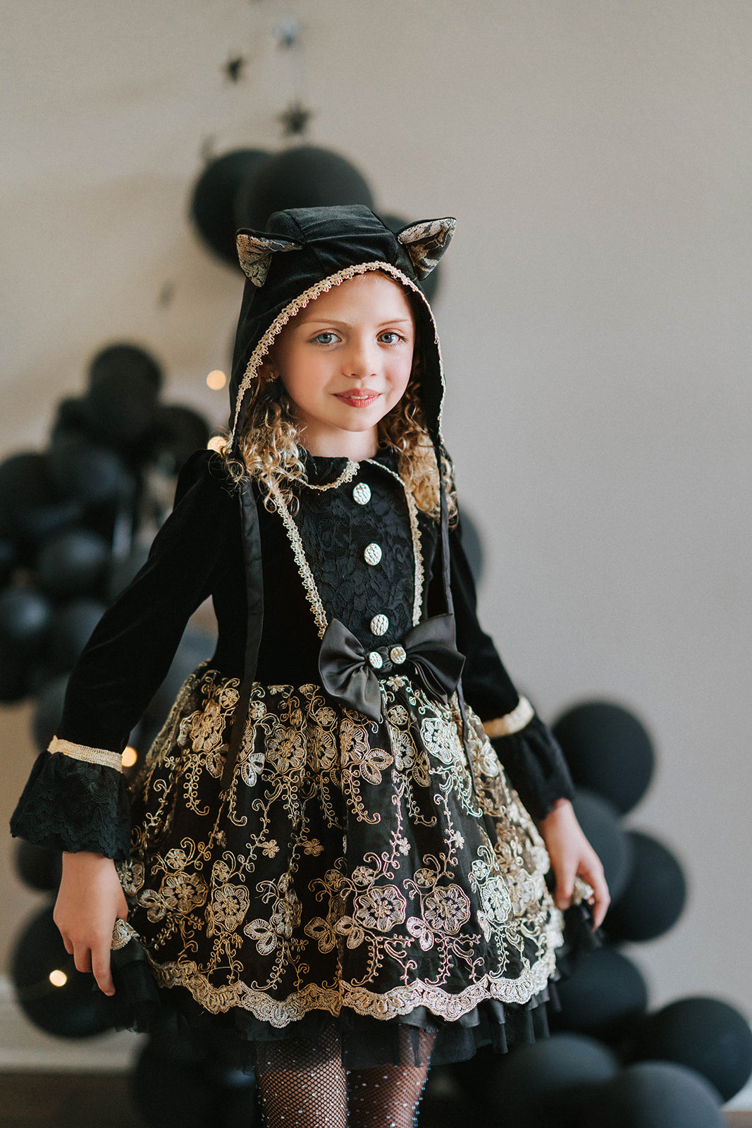 Elegant girls Halloween cat dress with hooded velvet top, gold lace trim, and full embroidered skirt, styled for spooky season

Gothic black and gold cat costume for girls with velvet hood, embroidered skirt, and satin bow, perfect for Halloween photoshoots

Child in hooded black cat dress with gold embroidery and velvet bodice, styled for Victorian Halloween or fairytale play

Girls velvet Halloween dress with cat ears, gold embroidered skirt, and ribbon bow, styled with tights and boots for a magical look