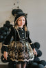 Elegant girls Halloween cat dress with hooded velvet top, gold lace trim, and full embroidered skirt, styled for spooky season

Gothic black and gold cat costume for girls with velvet hood, embroidered skirt, and satin bow, perfect for Halloween photoshoots

Child in hooded black cat dress with gold embroidery and velvet bodice, styled for Victorian Halloween or fairytale play

Girls velvet Halloween dress with cat ears, gold embroidered skirt, and ribbon bow, styled with tights and boots for a magical look
