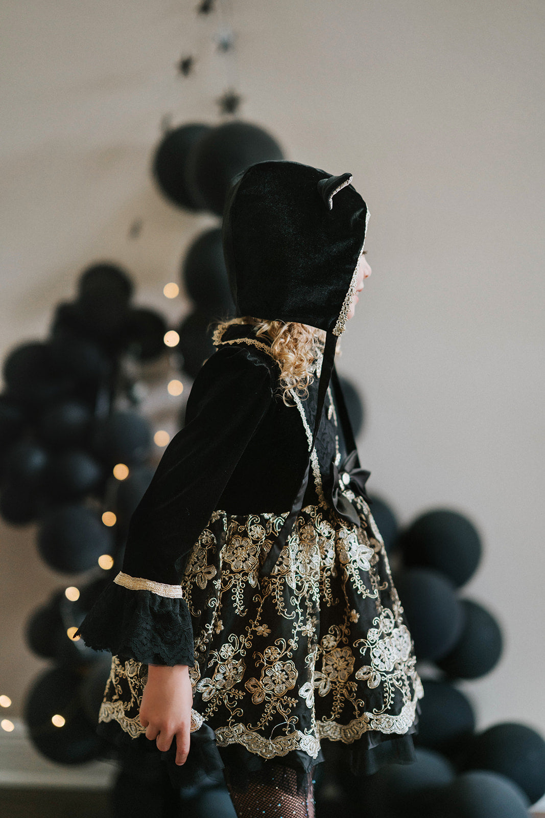 Elegant girls Halloween cat dress with hooded velvet top, gold lace trim, and full embroidered skirt, styled for spooky season

Gothic black and gold cat costume for girls with velvet hood, embroidered skirt, and satin bow, perfect for Halloween photoshoots

Child in hooded black cat dress with gold embroidery and velvet bodice, styled for Victorian Halloween or fairytale play

Girls velvet Halloween dress with cat ears, gold embroidered skirt, and ribbon bow, styled with tights and boots for a magical look