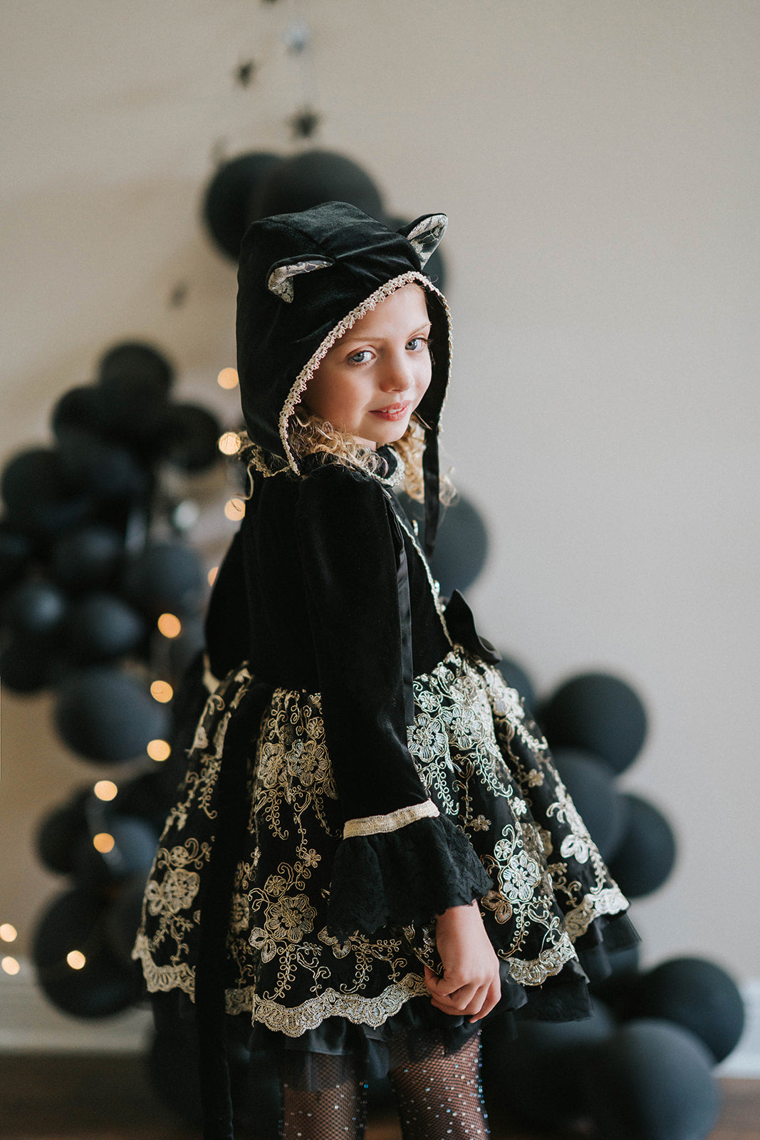 Elegant girls Halloween cat dress with hooded velvet top, gold lace trim, and full embroidered skirt, styled for spooky season

Gothic black and gold cat costume for girls with velvet hood, embroidered skirt, and satin bow, perfect for Halloween photoshoots

Child in hooded black cat dress with gold embroidery and velvet bodice, styled for Victorian Halloween or fairytale play

Girls velvet Halloween dress with cat ears, gold embroidered skirt, and ribbon bow, styled with tights and boots for a magical look