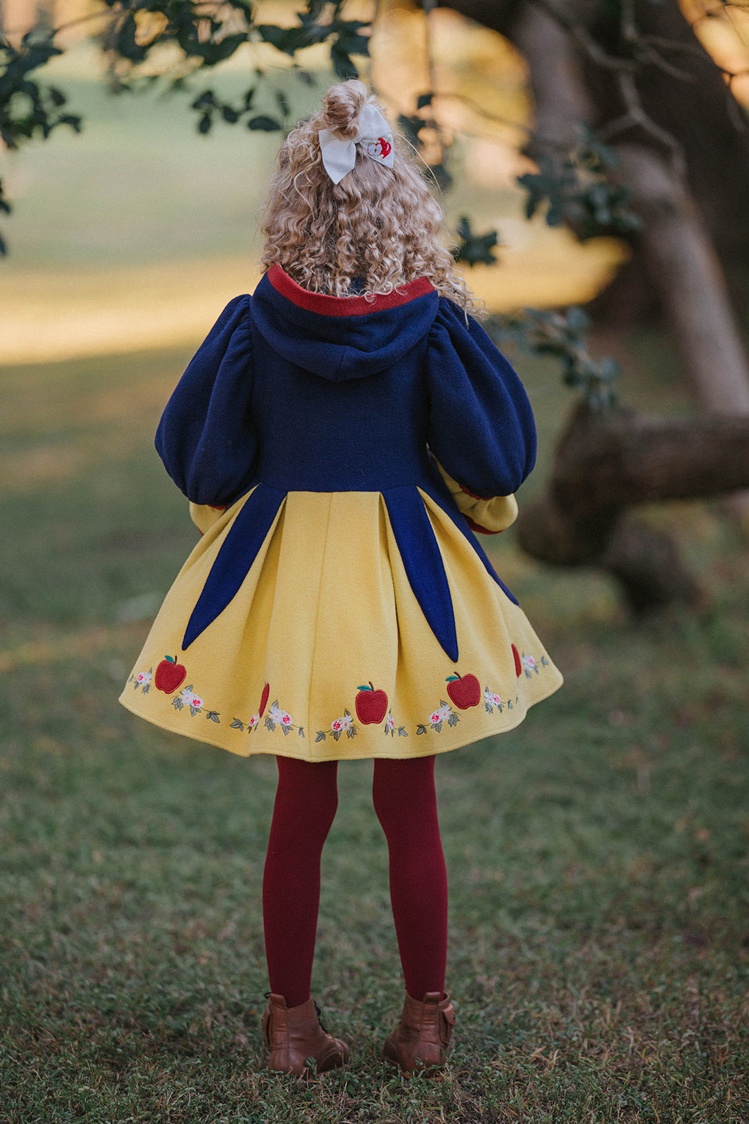 Child in Snow White style fall dress with puff sleeves, red bow, and apple details, perfect for princess costumes and Disney fans

Girls vintage-inspired Disney Snow White dress with floral and apple embroidery, red tights, and a fairytale woodland backdrop

Toddler to tween Snow White princess dress with navy bodice, yellow skirt, and red accessories, styled for magical portraits

Fairytale Disney princess dress inspired by Snow White with embroidered hem, oversized red bow, and classic storybook colors