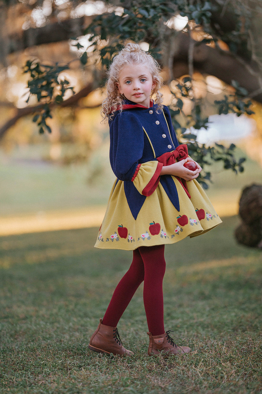 Girl wearing Disney Snow White–inspired princess dress with red bow, apple embroidery, and navy and yellow color palette in fairytale setting

Child in Snow White style fall dress with puff sleeves, red bow, and apple details, perfect for princess costumes and Disney fans

Girls vintage-inspired Disney Snow White dress with floral and apple embroidery, red tights, and a fairytale woodland backdrop

Toddler to tween Snow White princess dress with navy bodice, yellow skirt, and red accessories, styled for mag