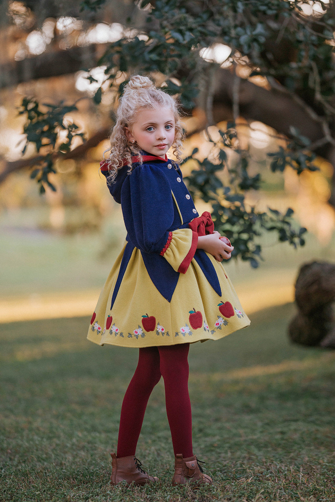 Child in Snow White style fall dress with puff sleeves, red bow, and apple details, perfect for princess costumes and Disney fans

Girls vintage-inspired Disney Snow White dress with floral and apple embroidery, red tights, and a fairytale woodland backdrop

Toddler to tween Snow White princess dress with navy bodice, yellow skirt, and red accessories, styled for magical portraits

Fairytale Disney princess dress inspired by Snow White with embroidered hem, oversized red bow, and classic storybook colors