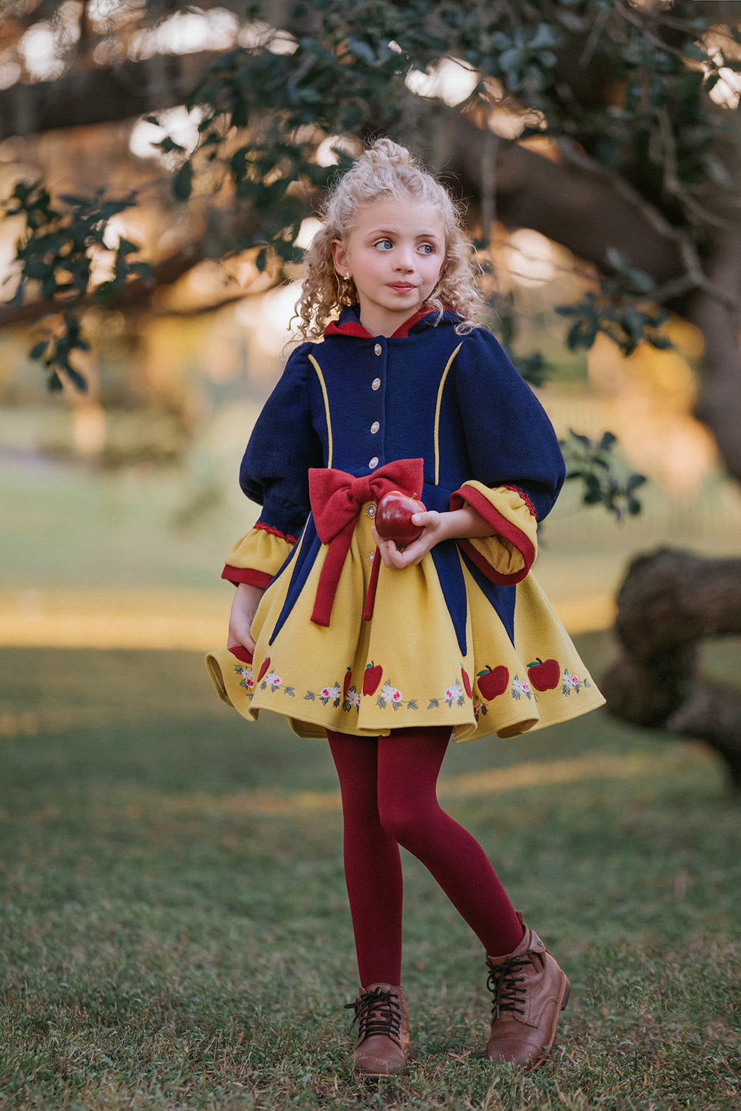 Girl wearing Disney Snow White–inspired princess dress with red bow, apple embroidery, and navy and yellow color palette in fairytale setting

Child in Snow White style fall dress with puff sleeves, red bow, and apple details, perfect for princess costumes and Disney fans

Girls vintage-inspired Disney Snow White dress with floral and apple embroidery, red tights, and a fairytale woodland backdrop

Toddler to tween Snow White princess dress with navy bodice, yellow skirt, and red accessories, styled for mag