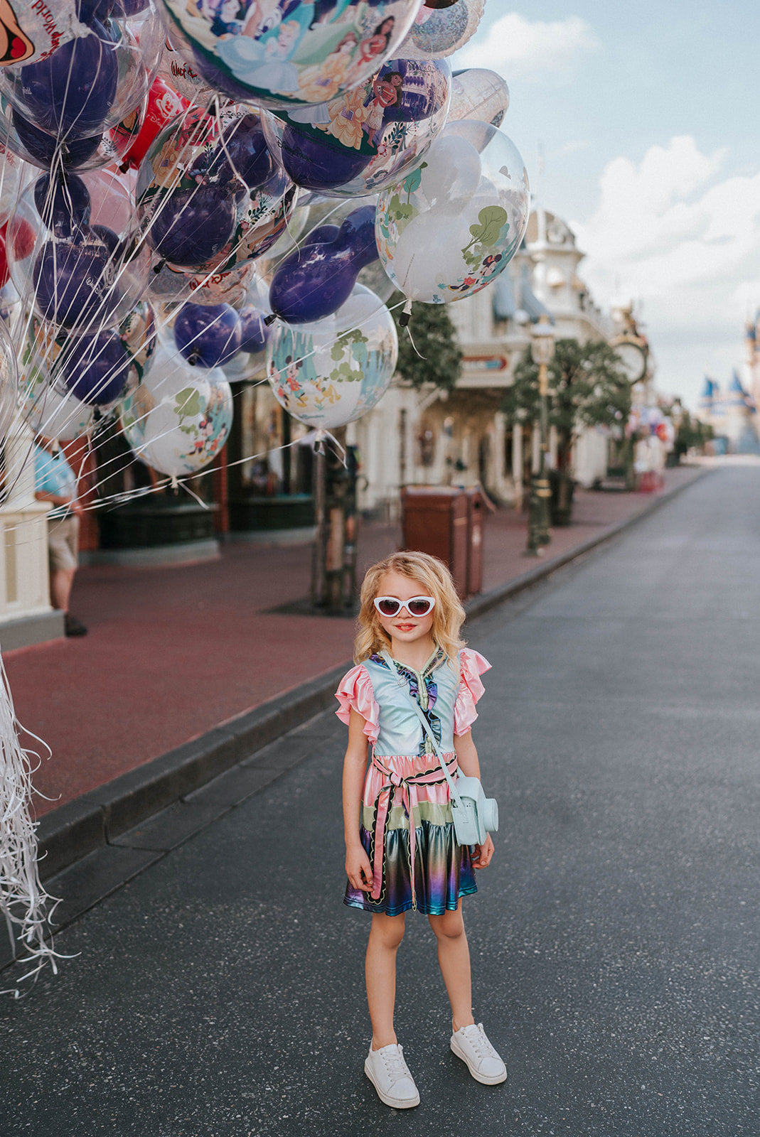 A vibrant metallic gown with colors of the rainbow. Pink flutter sleeves, tiered skirt perfect for twirling and a belted sash for that extra pizazz. 