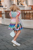 A vibrant metallic gown with colors of the rainbow. Pink flutter sleeves, tiered skirt perfect for twirling and a belted sash for that extra pizazz. 