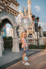 A vibrant metallic gown with colors of the rainbow. Pink flutter sleeves, tiered skirt perfect for twirling and a belted sash for that extra pizazz. 