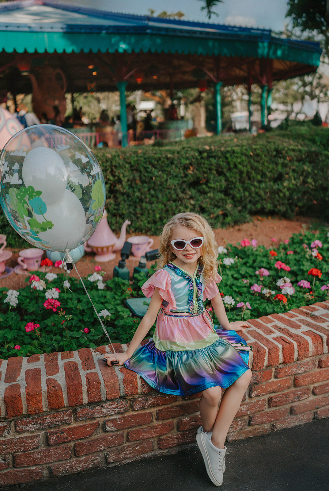 A vibrant metallic gown with colors of the rainbow. Pink flutter sleeves, tiered skirt perfect for twirling and a belted sash for that extra pizazz. 