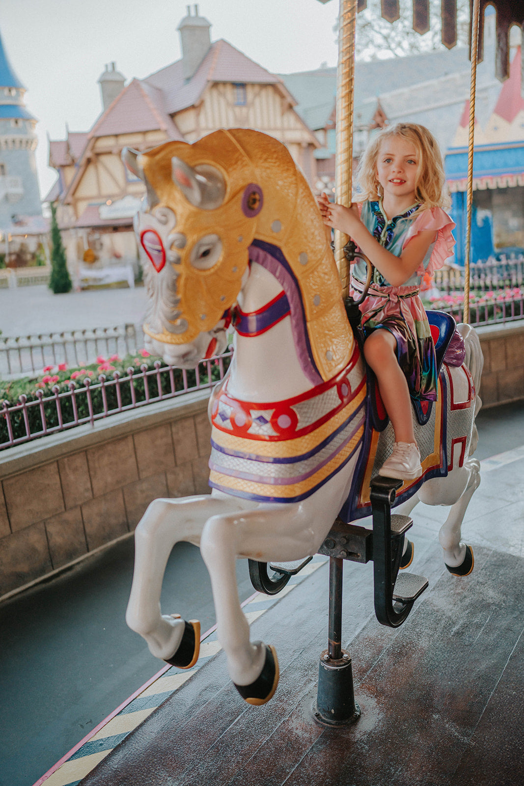 A vibrant metallic gown with colors of the rainbow. Pink flutter sleeves, tiered skirt perfect for twirling and a belted sash for that extra pizazz. 