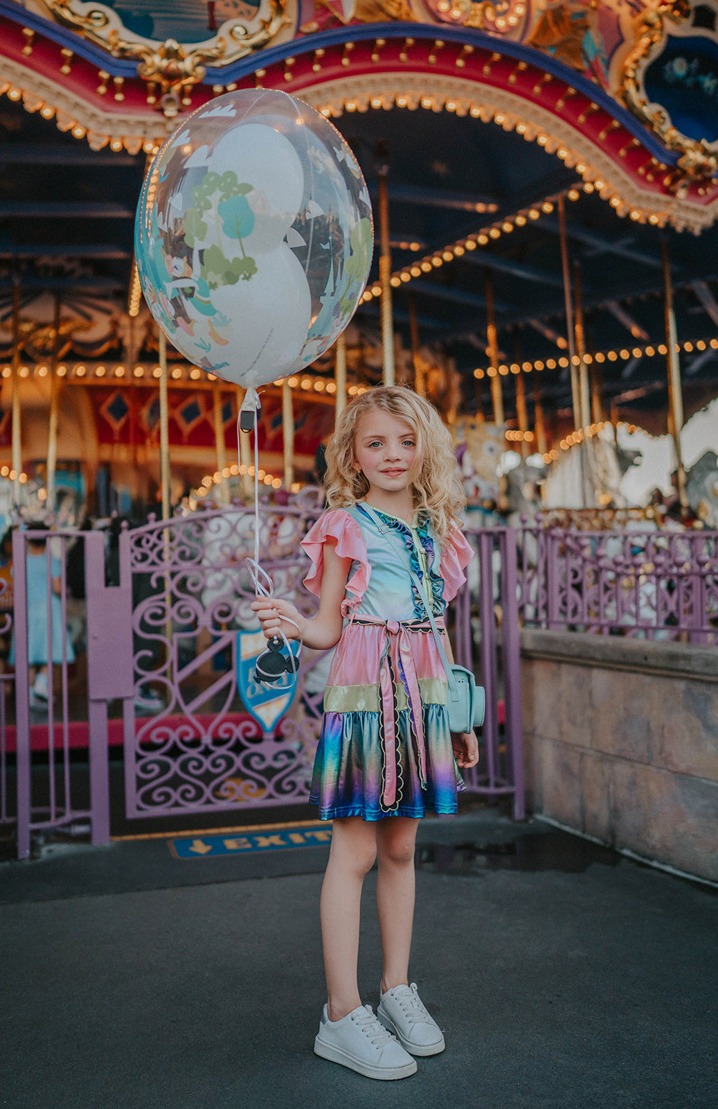 A vibrant metallic gown with colors of the rainbow. Pink flutter sleeves, tiered skirt perfect for twirling and a belted sash for that extra pizazz. 