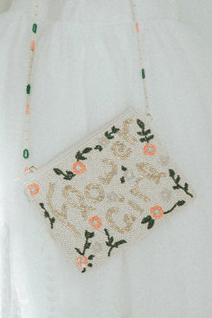 Beaded flower girl handbag with floral design and gold lettering on a young girl in white dress, perfect for weddings