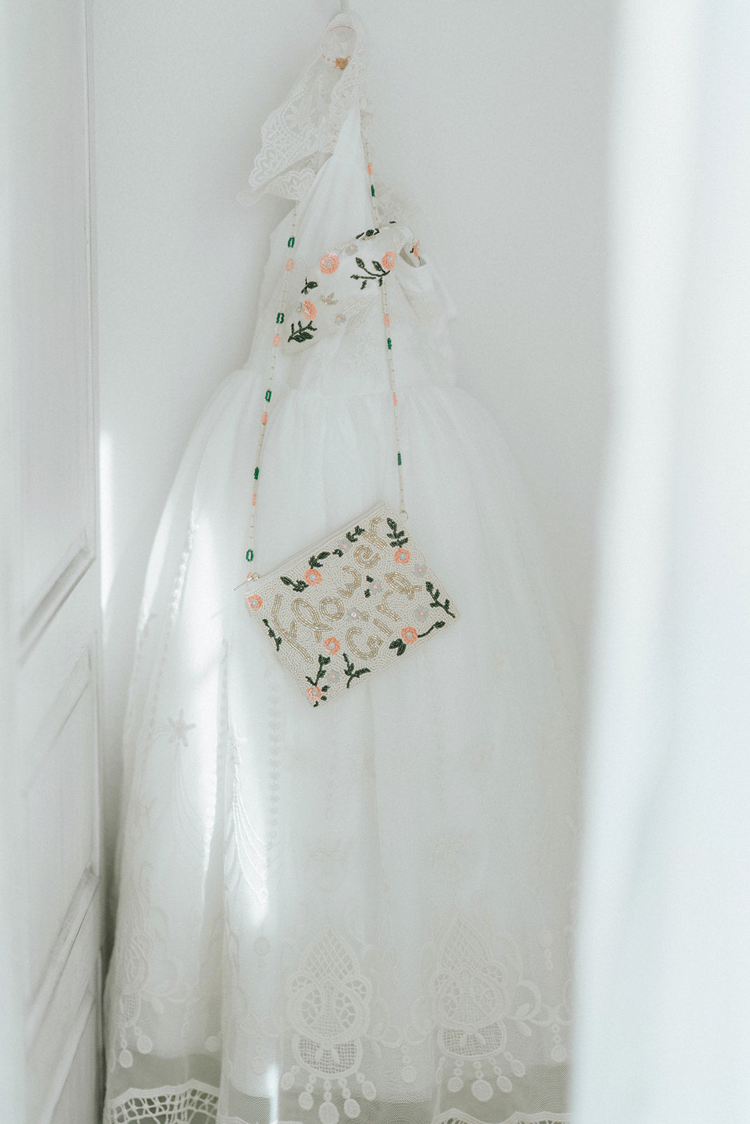 Beaded flower girl handbag with floral design and gold lettering on a young girl in white dress, perfect for weddings