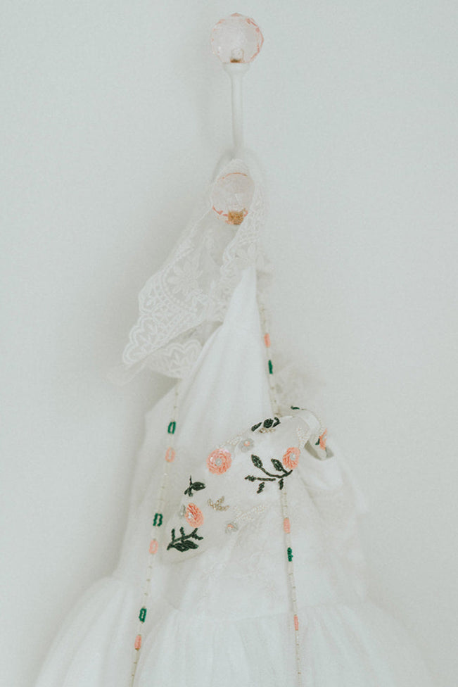 Beaded flower girl handbag with floral design and gold lettering on a young girl in white dress, perfect for weddings