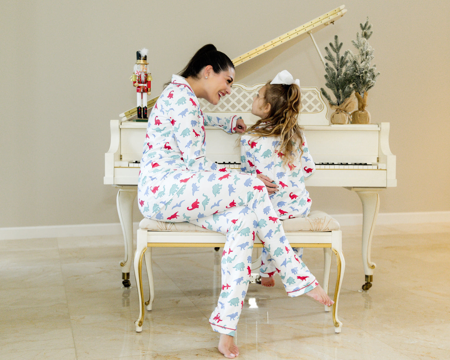 Mom and daughter wearing matching dinosaur pajamas in red, blue, and green print, cuddling and smiling in cozy indoor setting

Matching mommy and me dinosaur pajama set with colorful dino print, perfect for bedtime, holidays, or family photos

Mother and child snuggling in coordinating white dinosaur print pajamas with red piping, styled for cozy family moments