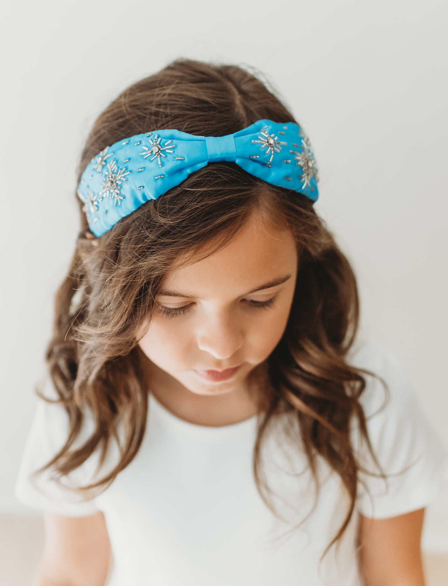 A bright blue satin headband with snowflake crystal beadwork.  Designed for all day comfort. 