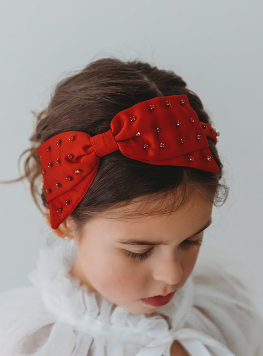 Our Snow White Headband is a true red.  There is a large red bow that lays flat adorned with red rhinestones.  The bow sits atop a matching headband. 