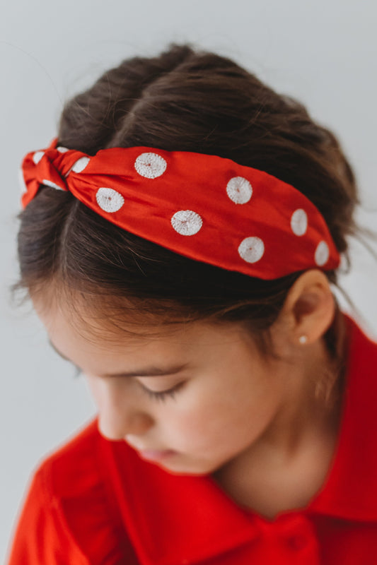 Our Miss Mouse Headband is red satin with white embroidered polka dots.  There is a knot at the center.  This hair accessory is versatile and can be styled many way.  The hair accessory is comfortable and designed for all day wear. 