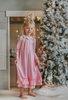 A young girl is wearing the Sleepy Who Gown inspired by Cindy Lou Who.  The buttery soft lounge wear has a white collar.  Light pink with small white polka dots and two adorable ruffles at the bottom. 