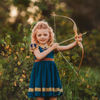 A young girl is wearing a dark teal cotton twirl dress.  The puff sleeves have metallic gold.  Metallic gold lines the neck with a dark teal jewel.  A intricate gold ribbon runs along the hem. 