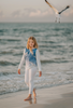 A young girl is wearing a stylish Seagull Soundtrack Shirt with a blue front panel featuring birds in flight, crafted from soft cotton jersey knit, paired with white leggings. 