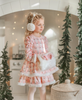 A young girl is wearing a long sleeve pink twirl dress adorned with white and silver ice skates.  The sleeves and hem of the twirl are lined with white faux fur.  There is a double layer skirt for excellent twirling.  Also included is a white faux fur hand muff with pink bow. 