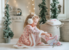 A young girl is wearing a long sleeve pink twirl dress adorned with white and silver ice skates.  The sleeves and hem of the twirl are lined with white faux fur.  There is a double layer skirt for excellent twirling.  Also included is a white faux fur hand muff with pink bow. 