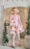 A young girl is wearing a long sleeve pink twirl dress adorned with white and silver ice skates.  The sleeves and hem of the twirl are lined with white faux fur.  There is a double layer skirt for excellent twirling.  Also included is a white faux fur hand muff with pink bow. 