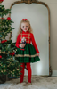 A young girl is wearing a toy soldier twirl dress.  The military collar leads into a cotton bodice adorned with gold thread detail that resembles a soldier uniform.  The evergreen chiffon skirt has multiple layers and is hemmed with gold.  The long sleeve dress is perfect for family holiday photos. 