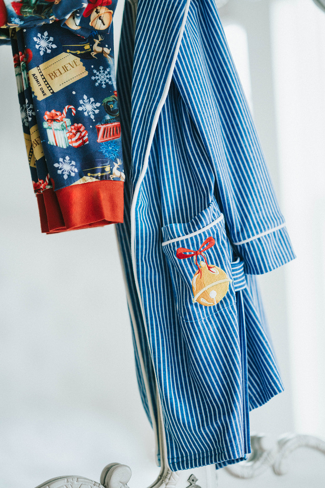 Close-up of child wearing blue striped Polar Express robe with gold bell embroidery on pocket and cozy Christmas pajamas underneath

Kids holiday robe inspired by Polar Express with white piping, gold bell patch, and tie waist, styled for Christmas morning

Blue and white striped Christmas robe with gold bell detail, worn by child with cozy holiday pajamas and slippers

Polar Express-themed unisex robe with gold bell embroidery and piping trim, perfect for kids’ Christmas sleepwear