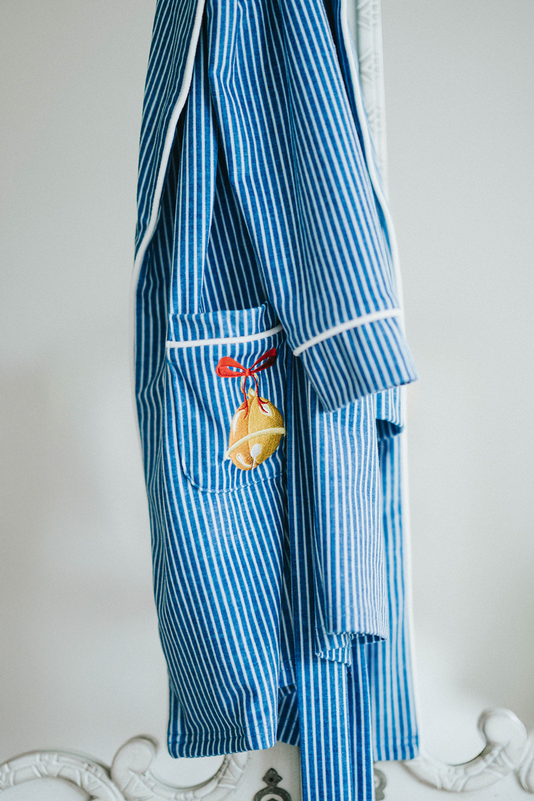 Close-up of child wearing blue striped Polar Express robe with gold bell embroidery on pocket and cozy Christmas pajamas underneath

Kids holiday robe inspired by Polar Express with white piping, gold bell patch, and tie waist, styled for Christmas morning

Blue and white striped Christmas robe with gold bell detail, worn by child with cozy holiday pajamas and slippers

Polar Express-themed unisex robe with gold bell embroidery and piping trim, perfect for kids’ Christmas sleepwear