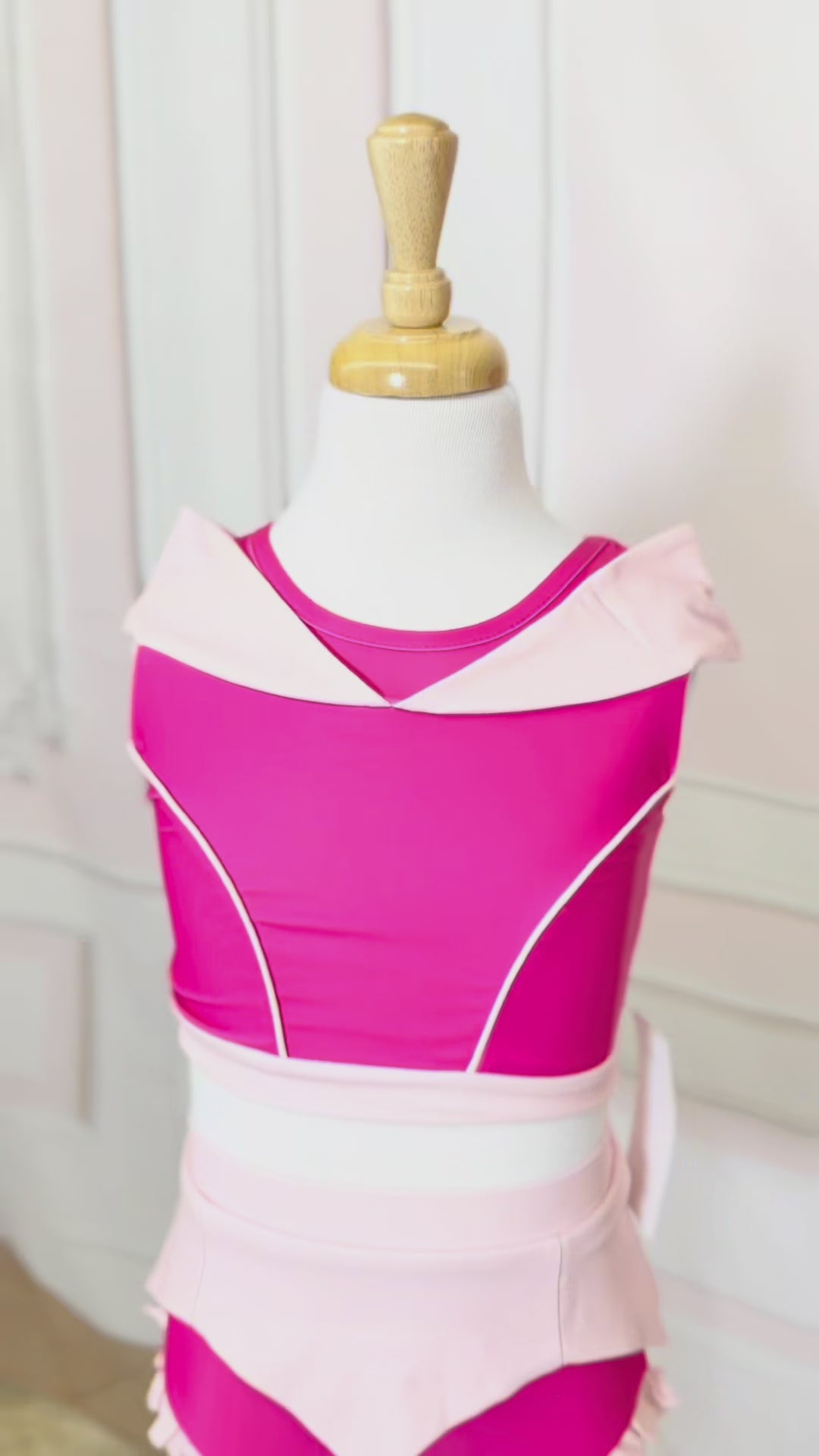  a pink 2 piece swimsuit.  The Sleeping Beauty swim set has a pink collar that resembles a ballgown.  The top has light pink piping and trim.  The modest bottoms have a pink overlay and ruffles on the legs. 