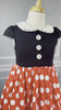 A young girl is wearing the Miss Mouse Twirl Dress, which features a black bodice, puff sleeves and a white collar.  Three white buttons decorate the center. The skirt is red with white polka dots and white eyelet lace trim.