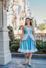 Eden is wearing our adult Cinderella Twirl dress.  The light blue dress has white ruffles on top of the blue straps. There is a white and blue bodice with a white peplum detail over the skirt. The light blue twirl skirt has a white ruffle hem. 