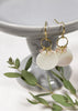 A golden hook with golden hoop and small crystal charms attaches to a large mother of pearl disc. 