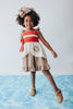 A young girl is wearing the Polynesian Princess Twirl Dress, which features beige and cream fabric accented by a red waistband and decorative floral embroidery.  There is a lace accent on the chest and ruffles on the top of the straps.  There is a ruffle on the hem and a tie on the side of the dress. Perfect for an adventurous princess. 