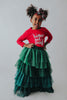 A young girl is wearing a long skirt in layers of green tulle.  The ruffles  cascade from green to evergreen.  There are 4 colors of green and 7 layers of tulle with a cotton liner for comfort. 