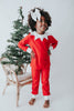 A young child dressed in Unisex Elf Pajamas with a red pointy hat. The perfect Christmas photo outfit. The fabric is bright red and buttery soft.  The top is long sleeved with white cuffs and a white collar that has large triangle points similar to a clown. Long pants with white cuffs. 