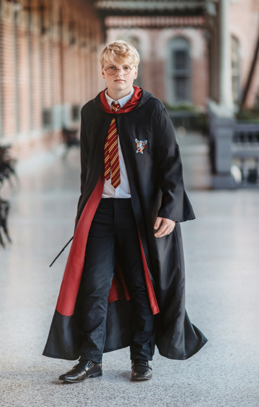 A young man is wearing our Adult Wizard Robe. The black robe has a Burgundy red lining to match your favorite wizards house colors.  There is an embroidered symbol on the left chest.  The robe has belle style sleeves and is ankle length. 