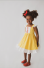 A young girl is wearing our Original Red Rose Twirl Dress from the Princess Twirl Collection. The sleeveless yellow dress features white ruffled trim and three red roses down the front. The sunny yellow dress provides a perfect princess twirl and soft comfortable cotton fabric. 