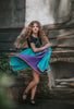 A young girl twirls in the vibrant Older Ice Princess Sister Set Style C dress, embellished with teal and purple accents. The removable cape is purple and teal with brown gold trim. The short sleeves feature a golden brown design.