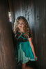 A young girl twirls in the vibrant Older Ice Princess Sister Set Style C dress, embellished with teal and purple accents. The removable cape is purple and teal with brown gold trim. The short sleeves feature a golden brown design.